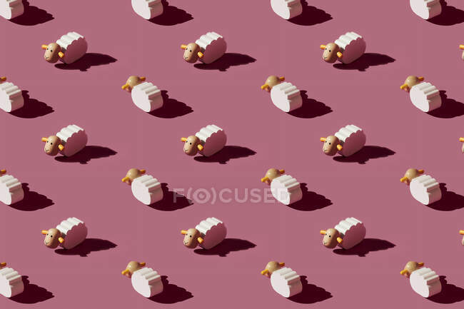 Pattern of small white sheep figurines against red background — Stock Photo