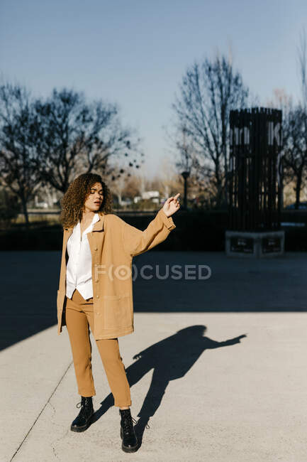Fashionable young woman with eyes closed standing on footpath during sunny day — Stock Photo