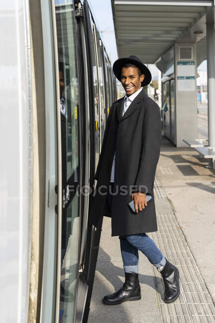 Щасливий молодий чоловік заходить на трамвай у сонячний день. — стокове фото