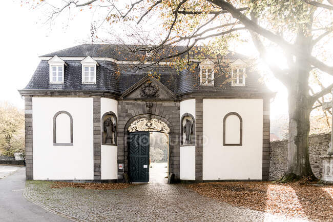 Германия, Северный Рейн-Вестфалия, Кенигсвинтер, Солнце, сияющее над входными воротами аббатства Хайстербах — стоковое фото