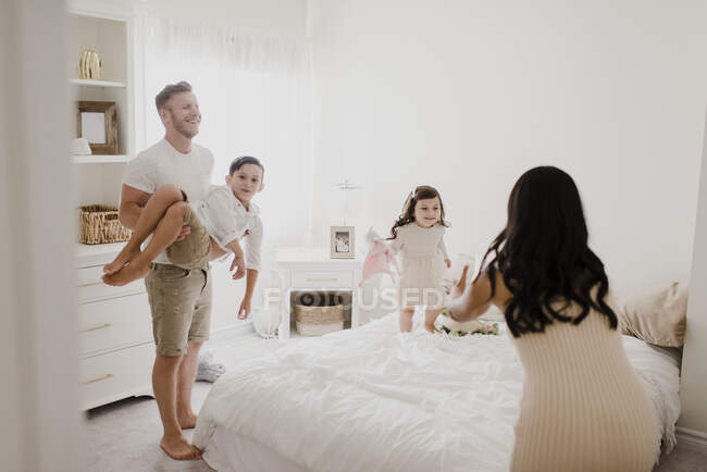 Playful family enjoying over bed in bedroom — Stock Photo