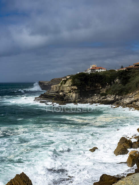 Portugal, Distrito de Lisboa, Azenhas do Mar, Olas salpicando por debajo de los acantilados de la ciudad costera - foto de stock