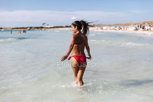 Щаслива жінка в бікіні, що ходить морем проти неба. — стокове фото