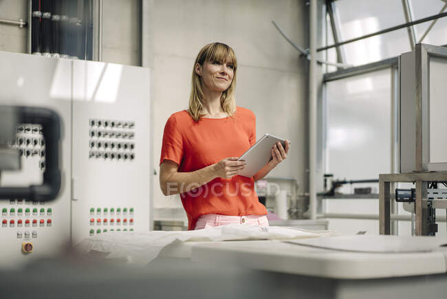 Женщина-предприниматель с цифровым планшетом, стоящая за столом в теплице — стоковое фото