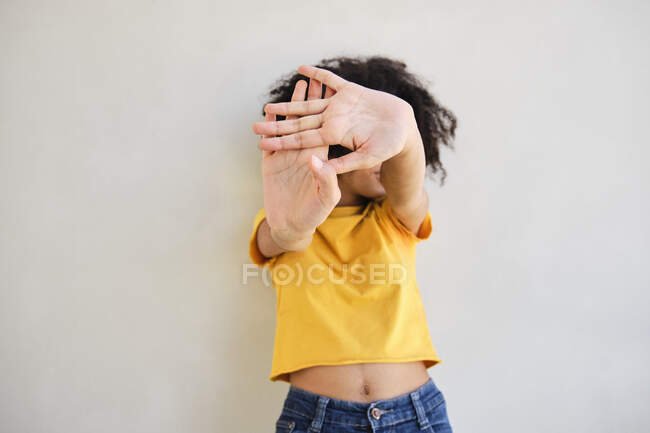 Frau zeigt Stopp-Geste, während sie gegen weiße Wand steht — Stockfoto