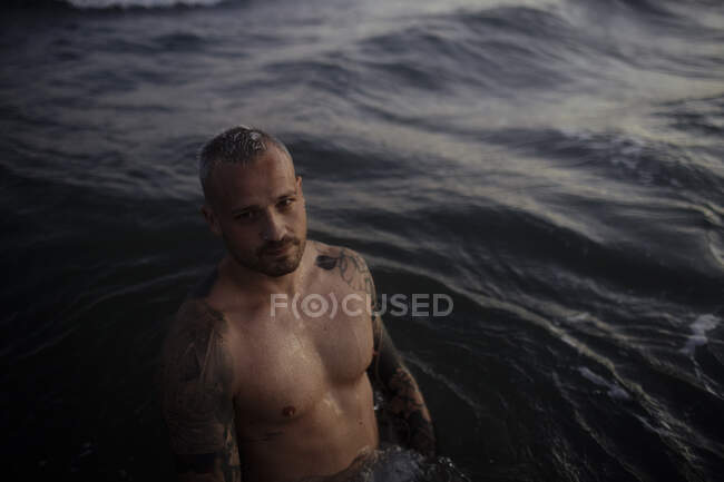 Sem camisa médio adulto homem de pé no mar — Fotografia de Stock