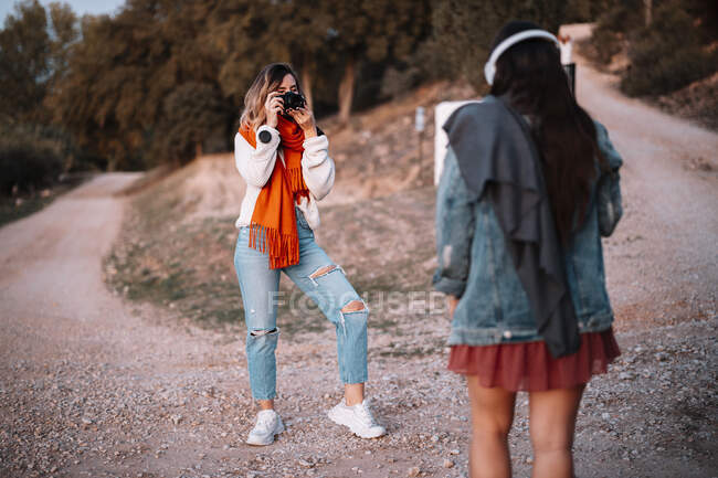 Giovane donna scattare foto di sorella sulla passerella nella foresta durante il tramonto — Foto stock