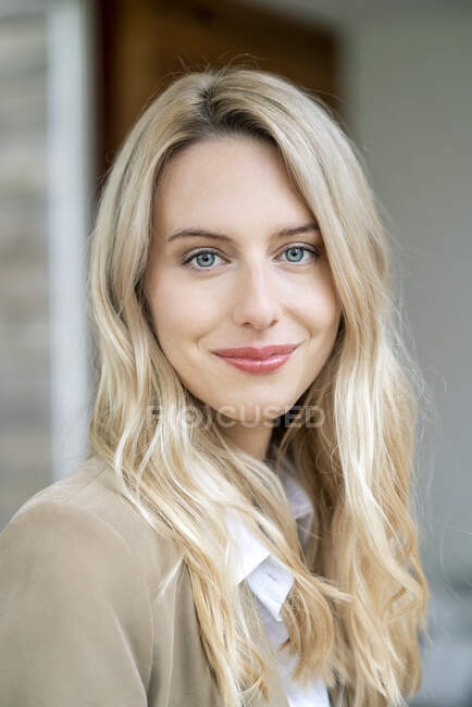 Крупный план улыбающейся предпринимательницы с светлыми волосами в офисе — стоковое фото