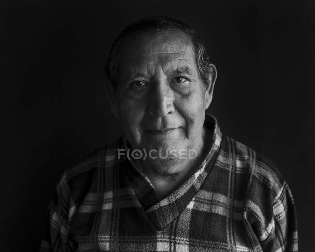 Hombre mayor sonriente contra fondo negro - foto de stock