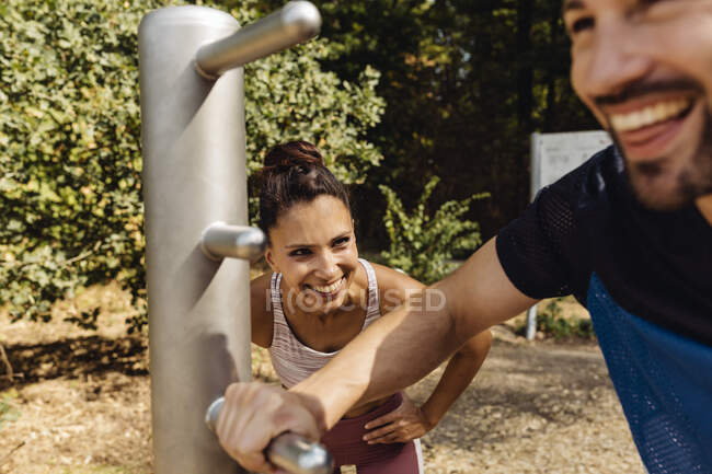 Mujer riéndose de hombre estirándose en un sendero de fitness - foto de stock