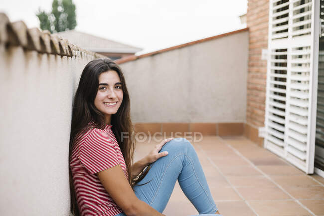 Sorrindo jovem mulher sentada na varanda — Fotografia de Stock