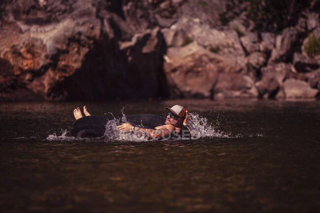 Uomo su tubo interno galleggiante nel fiume — Foto stock