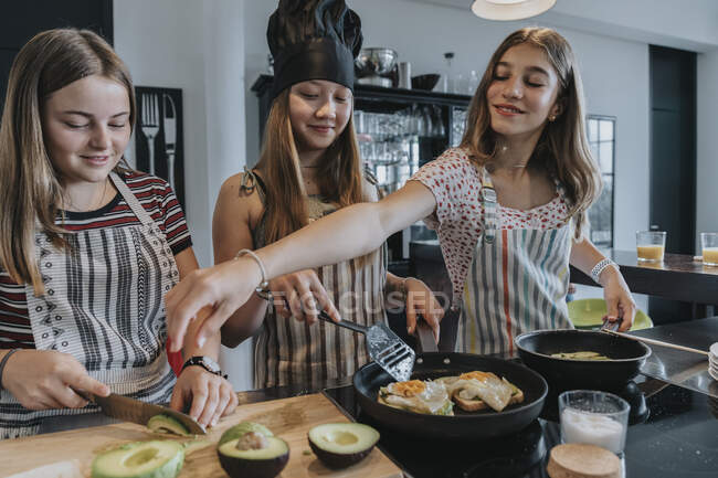 Дівчата готують здоровий обід разом, смажать яйця на кухні. — стокове фото