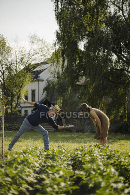Man giving laptop to woman while standing in backyard — Stock Photo