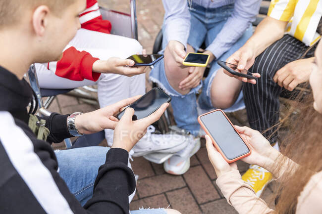 Amis utilisant des téléphones intelligents tout en passant du temps libre ensemble — Photo de stock