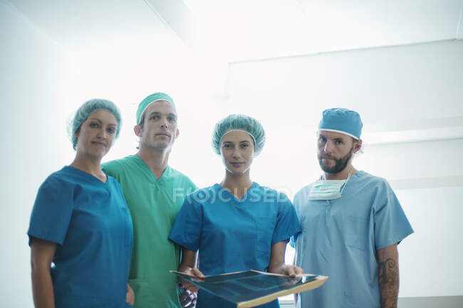 Впевнена команда хірургів, що стоять з медичним рентгенівським зображенням у лікарні — стокове фото