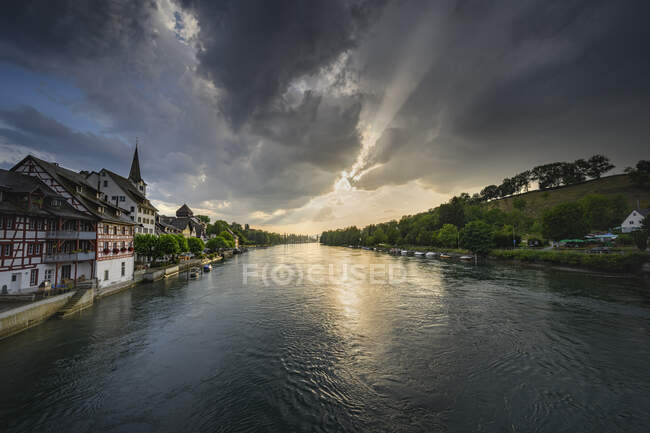 Suiza, Cantón de Thurgau, Diessenhofen, Alto Rin y pueblo adyacente al atardecer gris nublado - foto de stock