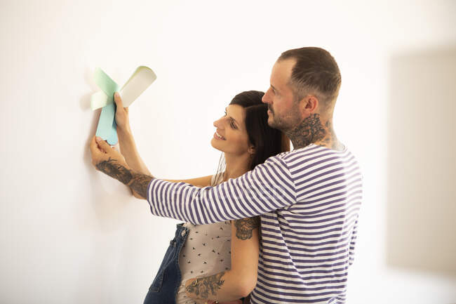 Пара выбирая через цветные образцы по стене в новом доме — стоковое фото