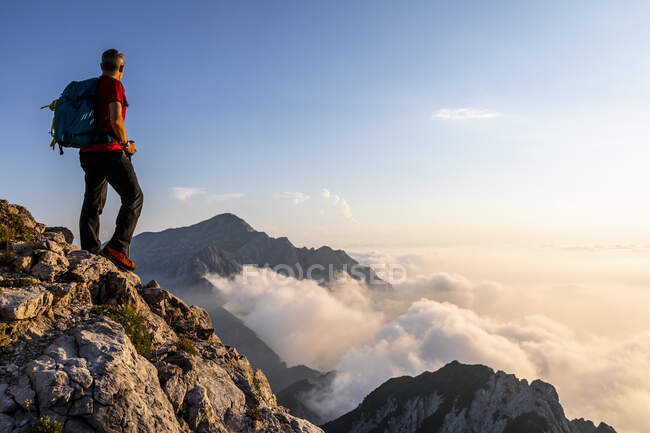 Hombre admirando la vista mientras está de pie en el pico de la montaña en los Alpes bergamascos, Italia - foto de stock