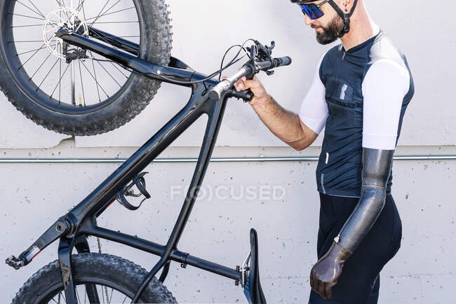 Athlète amputé masculin tenant un vélo debout par un mur — Photo de stock
