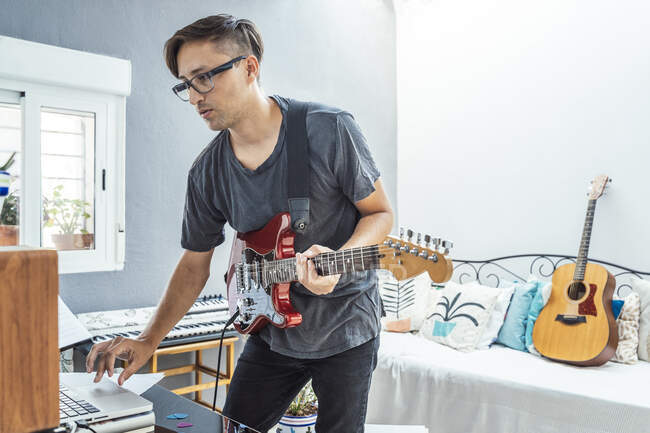 Musician with guitar using laptop at home — Stock Photo