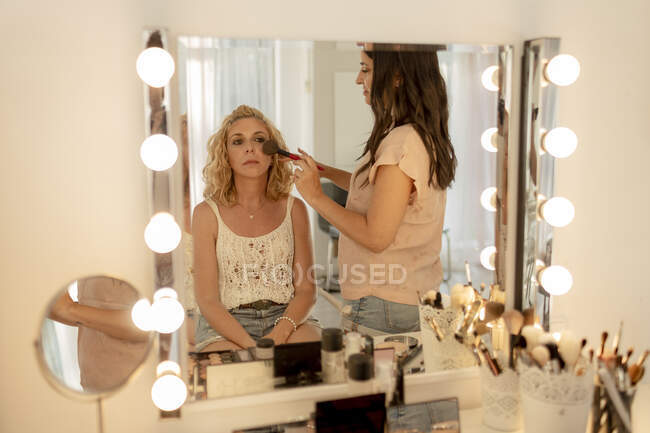 Make-up artist applicando blusher al cliente riflettendo sullo specchio in studio — Foto stock