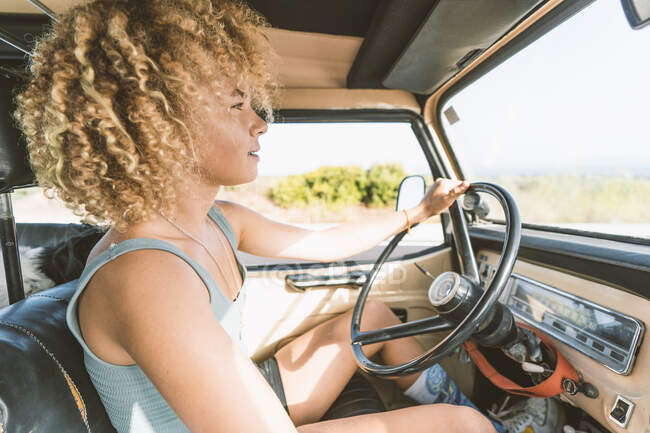 Young blond Afro woman sitting in old off-road vehicle — Stock Photo