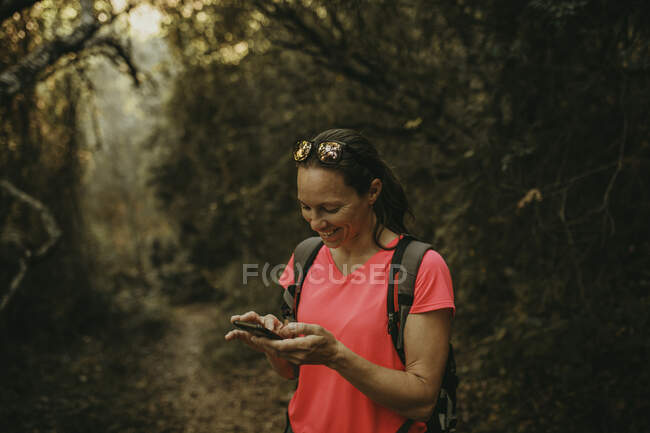 Mulher sorridente usando telefone celular em pé na Sierra De Hornachuelos, Córdoba, Espanha — Fotografia de Stock