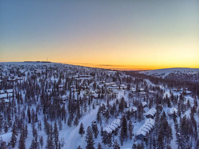 Finlândia, Lapónia, Saariselka, Vista aérea da aldeia montanhosa coberta de neve ao entardecer — Fotografia de Stock