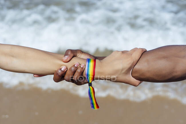 Primer plano de la pareja cogida de la mano sobre el mar en un día soleado - foto de stock