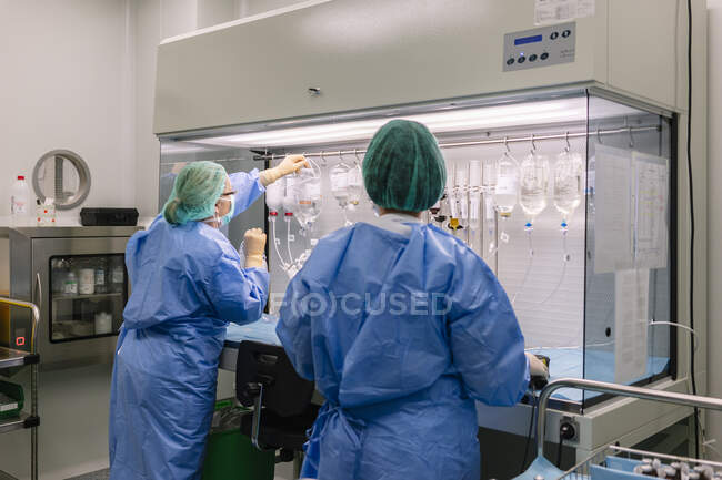Colleghe che organizzano iv gocce su rack in laboratorio — Foto stock