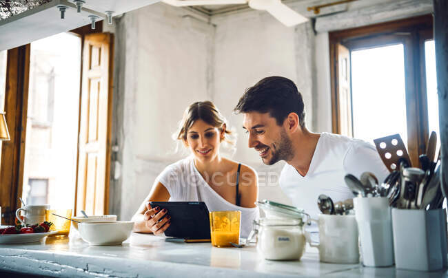 Young couple watching tablet while having breakfast at home — Stock Photo