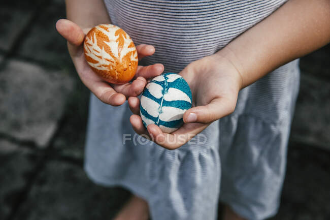 Manos de niña sosteniendo huevos de Pascua de color orgánico - foto de stock