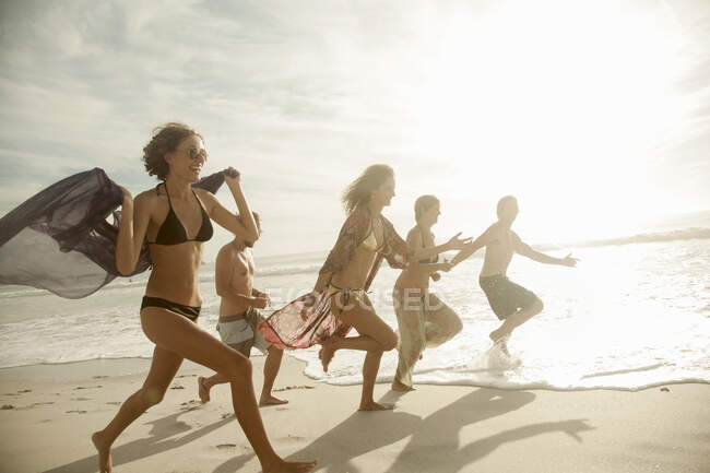 Група друзів біжить на пляжі в сонячний день. — стокове фото