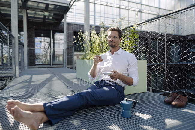 Homme professionnel avec café assis sur le sol dans la pépinière — Photo de stock
