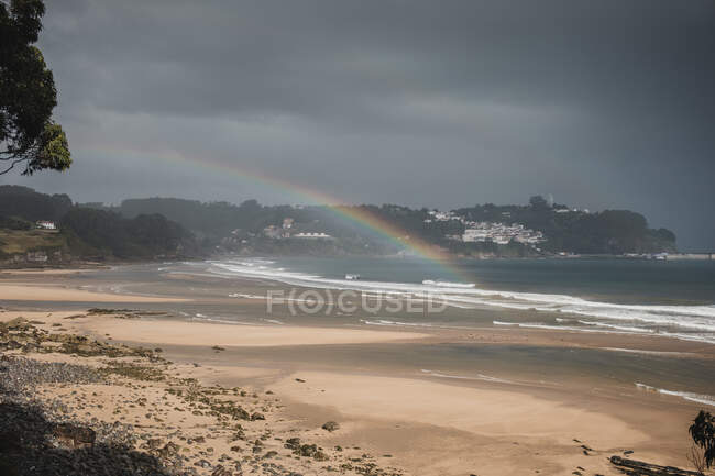 Vista del arco iris en la playa vista durante la temporada de lluvias - foto de stock