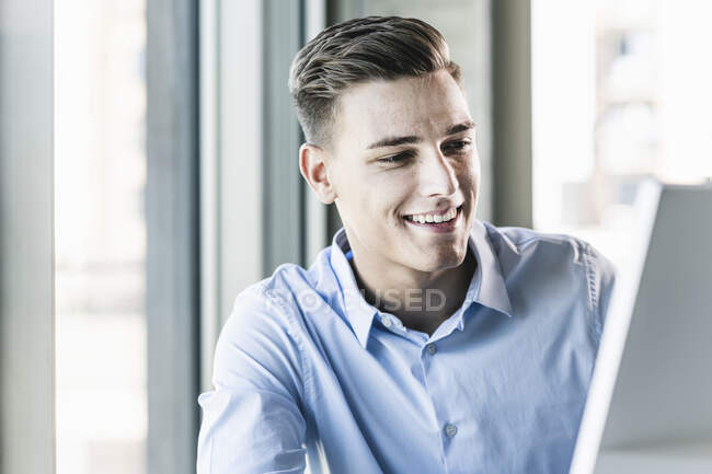 Close-up of smiling businessman looking at computer in office - foto de stock