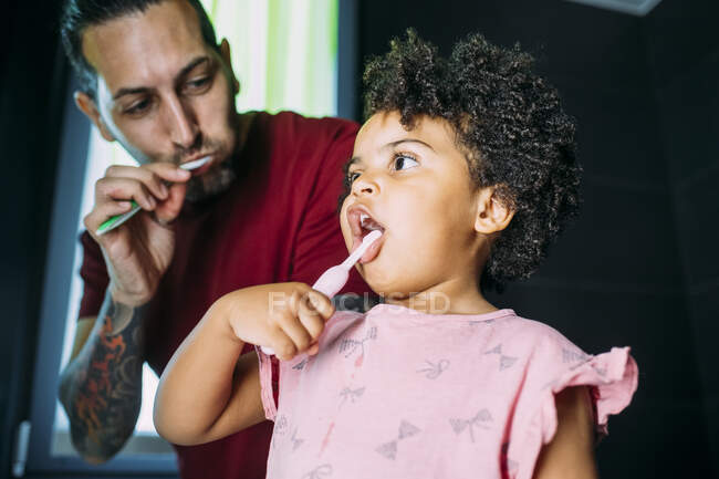 Close-up of daughter with father brushing teeth in bathroom at home — Stock Photo