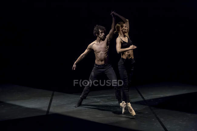 Dançarino masculino e feminino realizando balé contemporâneo no palco preto — Fotografia de Stock