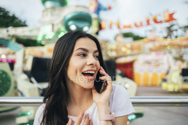 Primo piano di una donna allegra che parla tramite smart phone al parco divertimenti — Foto stock