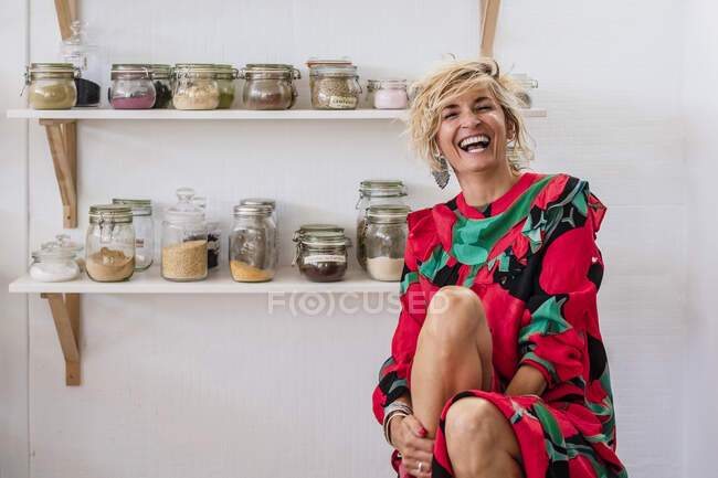 Веселая женщина-инструктор сидит напротив стойки специй на кухне — стоковое фото
