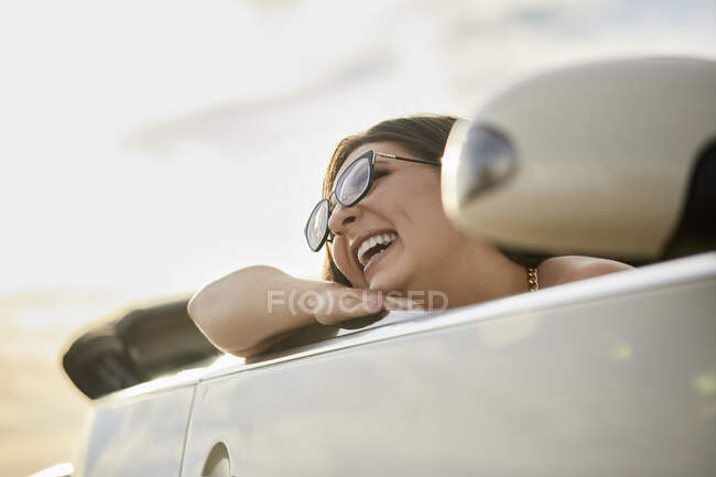 Fröhliche Frau lacht, während sie im Cabrio auf Roadtrip sitzt — Stockfoto