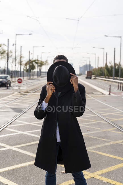 Giovane volto di copertura con cappello tra binario ferroviario su strada — Foto stock
