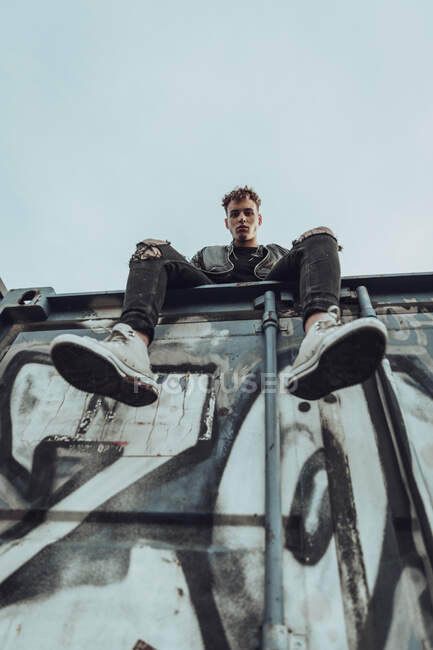 Модный молодой человек на металлическом контейнере против неба — стоковое фото