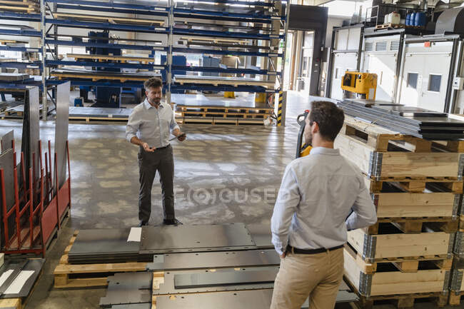 Business people standing by equipment while having discussion at factory — Stock Photo