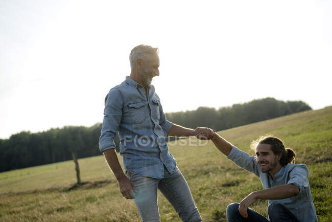Щасливий батько з дорослим сином на лузі в сільській місцевості. — стокове фото