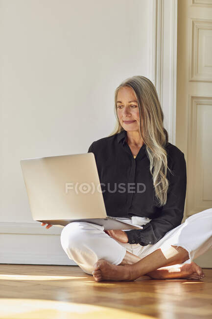 Donna che utilizza il computer portatile mentre seduto sul pavimento a casa — Foto stock
