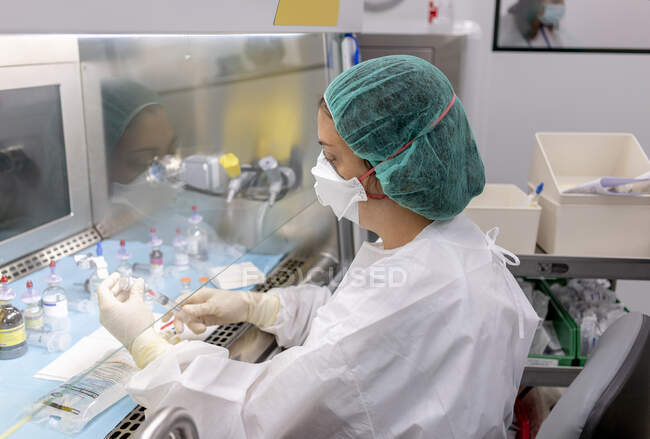 Pharmacienne injectant du liquide en flacon pendant qu'elle travaillait en laboratoire — Photo de stock