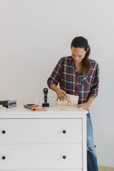 Mid adult woman  marking on wood while doing DIY work at home — Stock Photo
