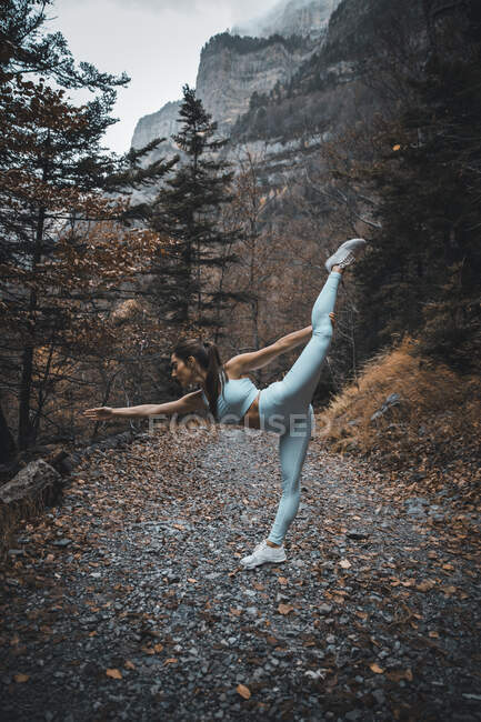 Jovem esportista fazendo ginástica rítmica enquanto está de pé na floresta — Fotografia de Stock